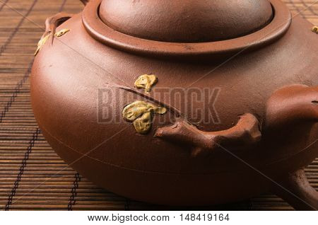 brown Chinese teapot of Yixing clay with traditional ornament on bamboo Mat