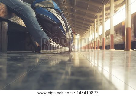 Traveler wearing backpack waiting for a train at trainstation and planing for next trip.Vintage tone Retro filter effect Soft focus Low light.(selective focus)