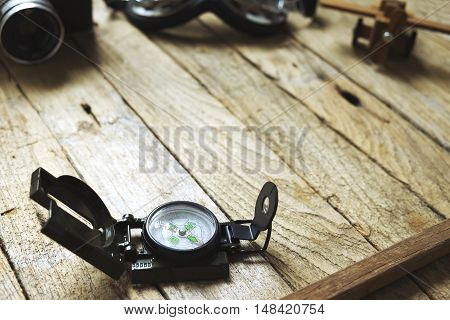Compass on wooden background. Blur vintage camera glasses and balsa wood model airplane. Vintage filter travel concept.