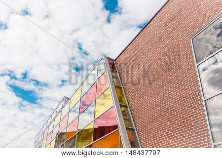The modern shopping center with colored windows on a background of a bright sky with clouds