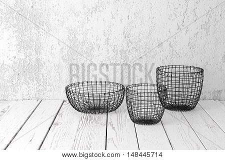 Vintage wire baskets on white wooden rustic floor industrial wicker storage bins