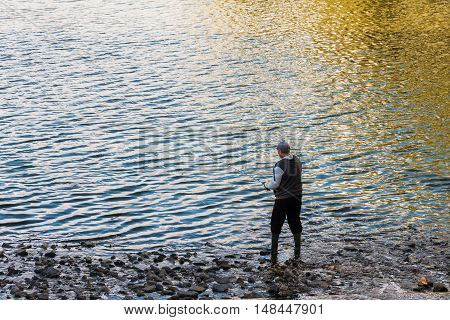 A man fishes in the River in the evening