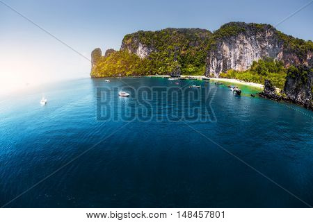 Aerial view of the sea with rocky island and anchored yacht in the bay.