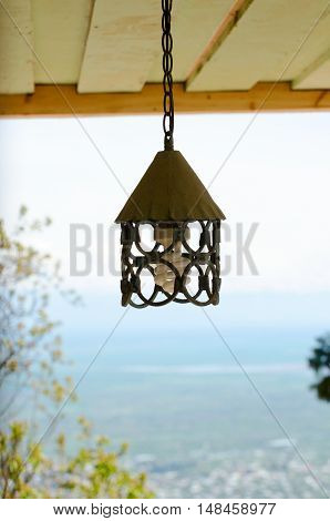 Forged metal a plafond on a chain under the wooden ceiling