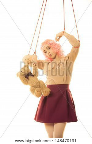 Mental disorder concept. Young woman girl stylized like marionette puppet on string with teddy bear toy on white background