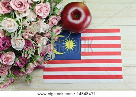 National day : Malaysia flag, apple and flower on wood background