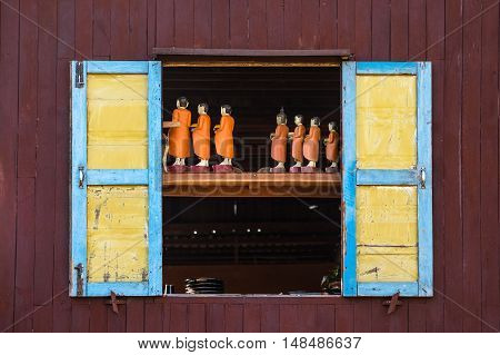 Traditional handicraft monk wooden doll in old window, Myanmar