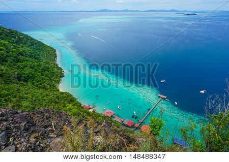 View from the peak of Bohey Dulang Island,Sabah,Borneo.Mirror smooth ocean surrounded by mountains.The bright blue water and rocky shore in the tropical island of Semporna,Sabah,Borneo.