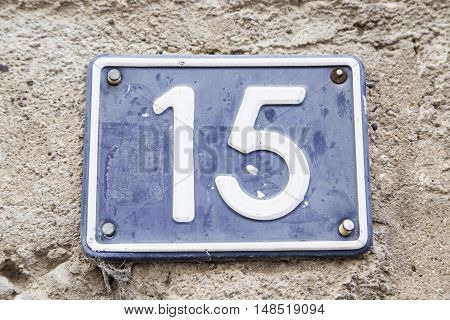 Number fifteen in a wall of a house detail of a number of information odd number