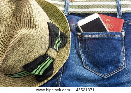 Passort and mobile phone in the pocket of blue jeans and a straw hat with bow a man goes on a big journey