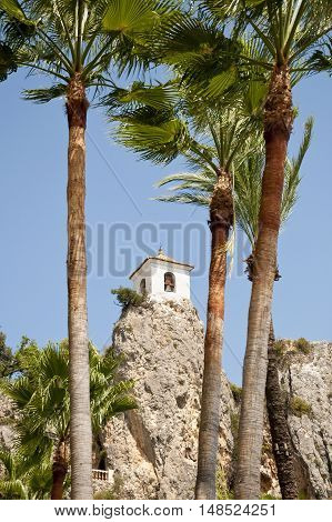 Belfry behind Palm Trees. This tower belongs to Alcozaiba fortress built by muslims at XI century. Picture taken in El Castell de Guadalest Alicante Spain.