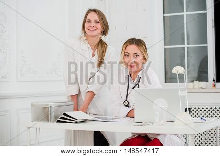 Two Female friendly cheerful Doctors or Nurses Isolated in office smiling and looking at camera.
