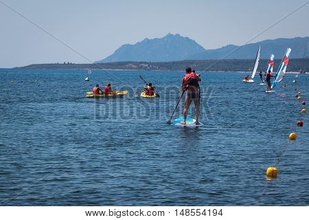 Stand Up Surfer Man Paddleboarding On Board Among Canoes And Windsurf
