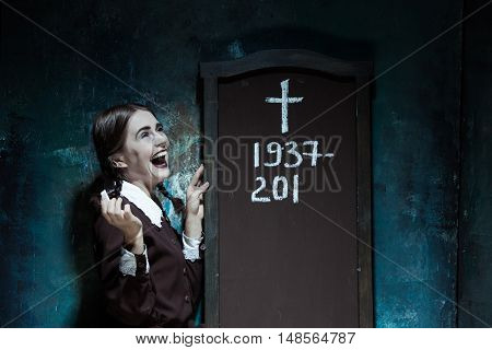 Halloween theme: Portrait of a young smiling girl in school uniform as killer woman against school board . The image in the style of Halloween and Addams family