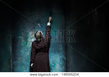 Halloween theme: Portrait of a young smiling girl in school uniform as killer woman against school board . The image in the style of Halloween and Addams family