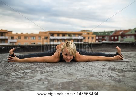 Beautiful woman practicing yoga on the roof,Upavista konasana