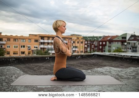Woman is practicing yoga on the roof.