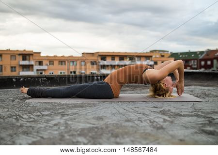 Woman practicing yoga on the roof,Fish pose/ Matsyasana