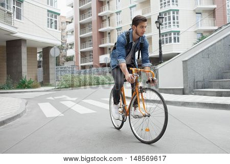 Guy in denim jacket going down the stairs holding an orange bicycle. Student with the bike going down