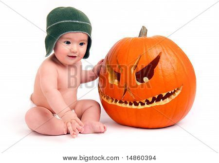 Young Boy Sits in Diaper with Carved Halloween Pumpkin