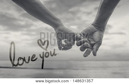 close up hand of senior couple hook each other's little finger together near seaside at the beach,black and white picture color,selective focus,love forever concept,text love you