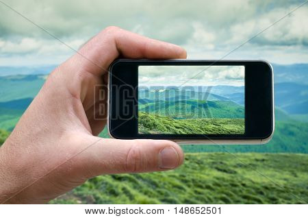 phone in hand man photographing the landscape photos from your phone, Selfie, photographing on the phone, the man photographs the mountain landscape on the phone smartphone side view. carpathians