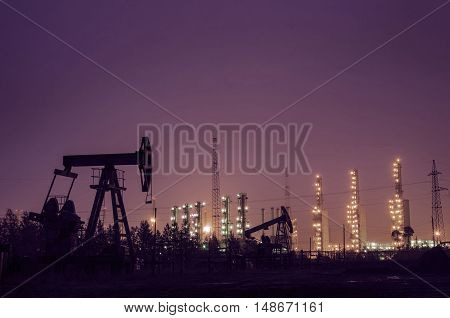 Oil rig at the background of refinery by night. Oil and gas industry. Toned.