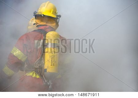 fireman in fire fighting suit working surround with smoke