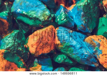 Pebbles painted bright colored paint. Stony surface covered with different colors. Abstract background.