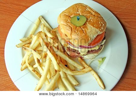 Fancy cheeseburger with french fries served on white plate in restaurant