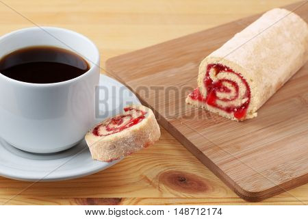 Sweet Roll With Jam On A Cutting Board. Cup Of Tea On A Wooden Table.