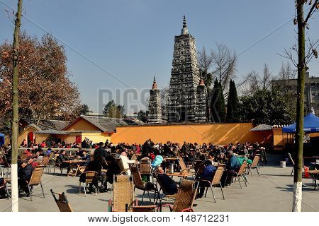 Pengzhou China - November 27 2013: Crowds of Chinese gather to sip tea and relax in the large courtyard in front of the Five Star Pagoda at the Long Xing Temple