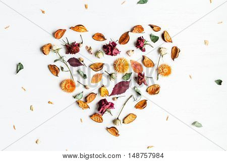 Autumn composition. Heart symbol made of dried flowers and autumn leaves top view flat lay