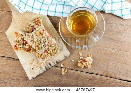 Crispy grains granola bar or rice biscuits with a glass cup of hot tea on wood table.