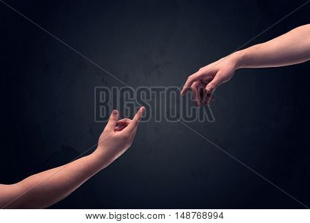 Two male hands reaching out to one another, almost touching, in front of dark clear empty background wall concept