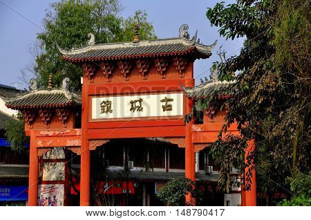 Pixian China - November 3 2009: Wooden red ceremonial entry gate with flying eave roofs and dragon figures stands at the south end of the town