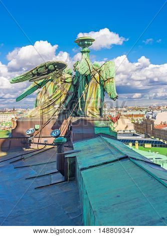 The bronze sculpture of angels holding the torch on the rooftop of the St Isaac's Cathedral with the city's skyline on the background St Petersburg Russia.