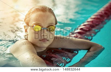 Swimmer child. Portrait of swimming child athlete with goggles after training in waterpool.