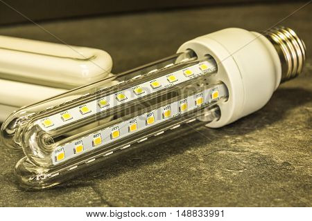 LED bulb in shape similar to a saving CFL bulbs in the foreground of the original CFL bulbs