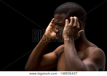 Portrait of Afro-American man having headache over black background. Handsome man with short hair touching his head in studio.