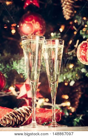 Two Glasses Of Champagne With Christmas Tree Background. Holiday Season Background. Traditional Red