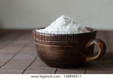 Salt in a brown ceramic bow on a wooden tablel. Rustic still life