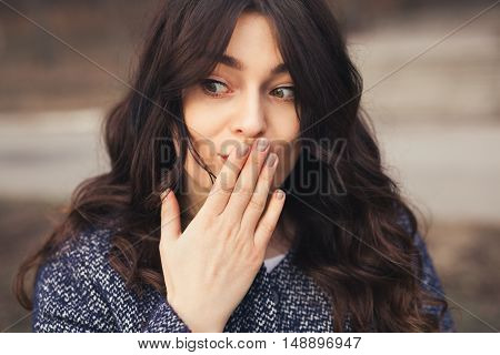 beautiful brunette woman. Oops concept Close up plus size girl holding hand on mouth. Female did a mistake