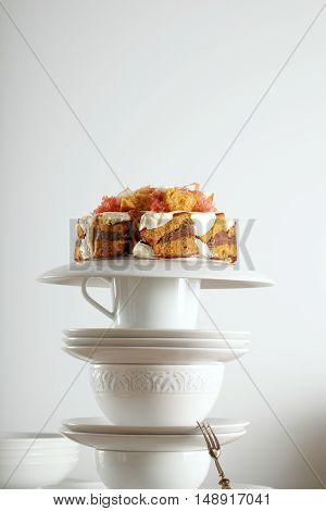 White vintage teaware and silver dessert spoon with a nontraditional wedding cake with chocolate, cream and fruit on top