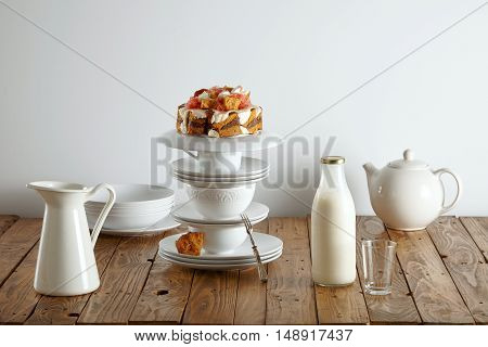 Modern white teaware, a milk bottle and a light brown sponge cake with cream, chocolate filling and grapefruit decorations