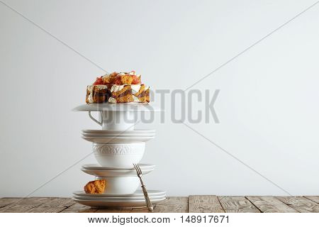 Pyramid of beautiful white porcelain cups and saucers with a nontraditional wedding cake on top