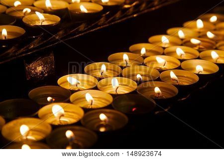 Rows of burning candles in a dim church