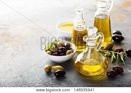 Olive oil in vintage bottles with black and green olives and leaves copyspace on rustic background