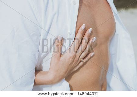 Sexy muscular naked man and female hands unbuckle his jeans.