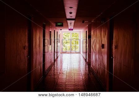 Red creepy hotel corridor with bright window at the end. Abstract Horror background.